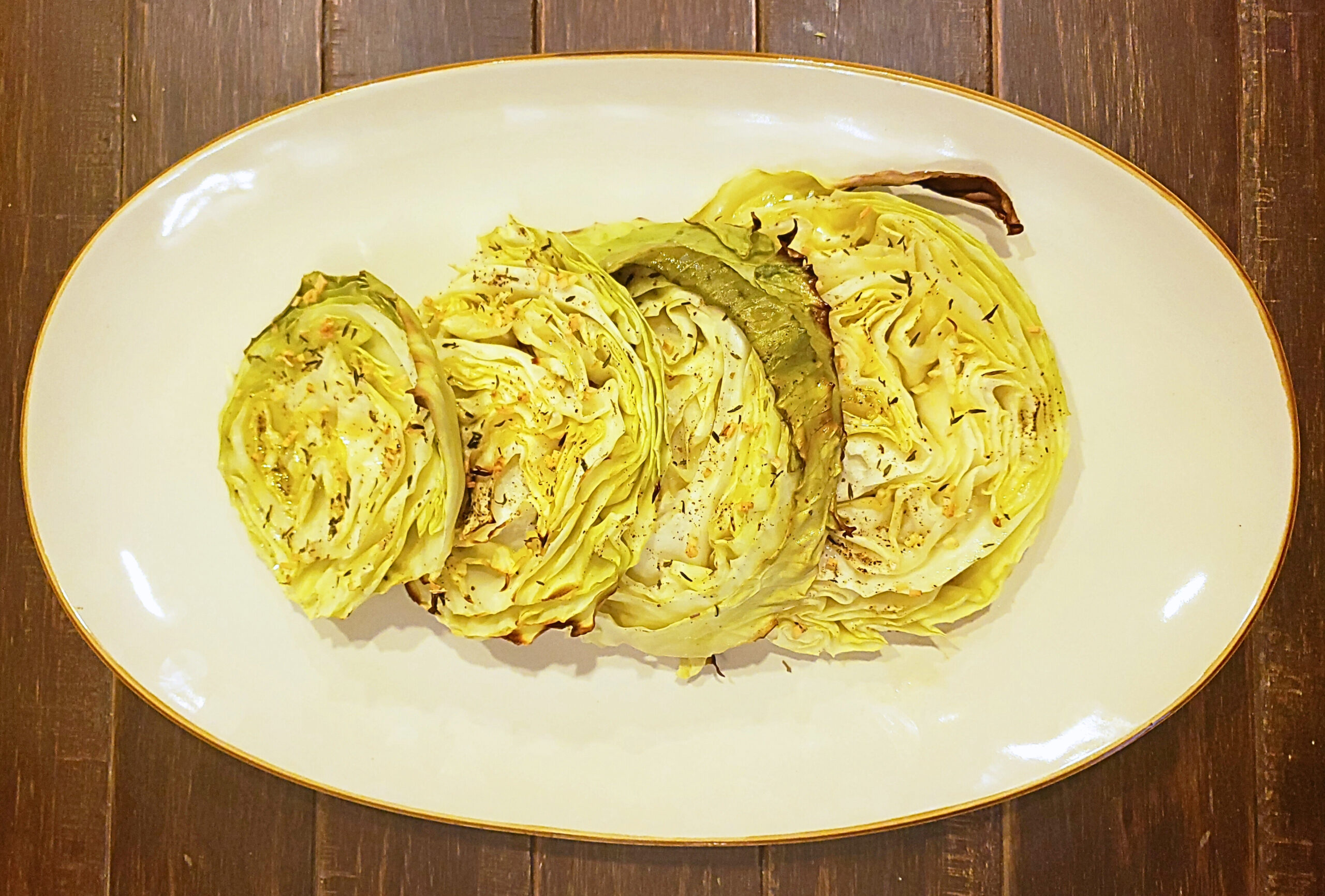 Cooked cabbage steaks on a cream colored plate
