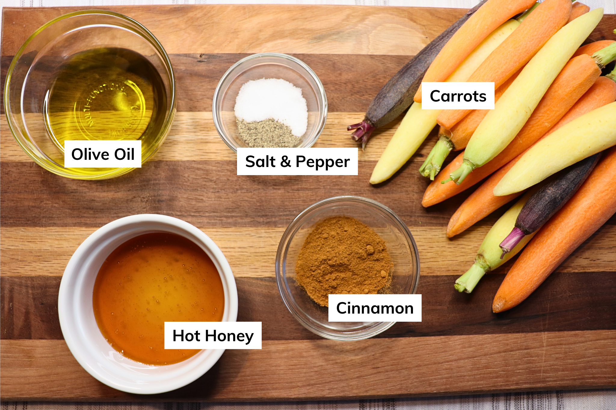 Ingredients for hot honey roasted carrots on a wooden cutting board