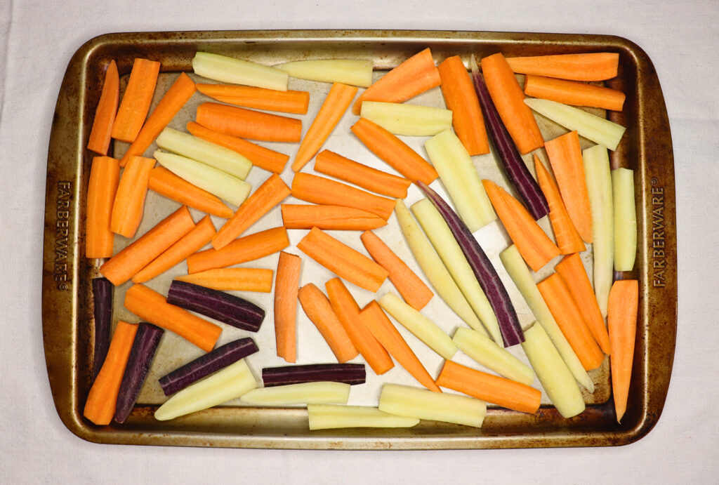Carrots cut into batons on a baking sheet