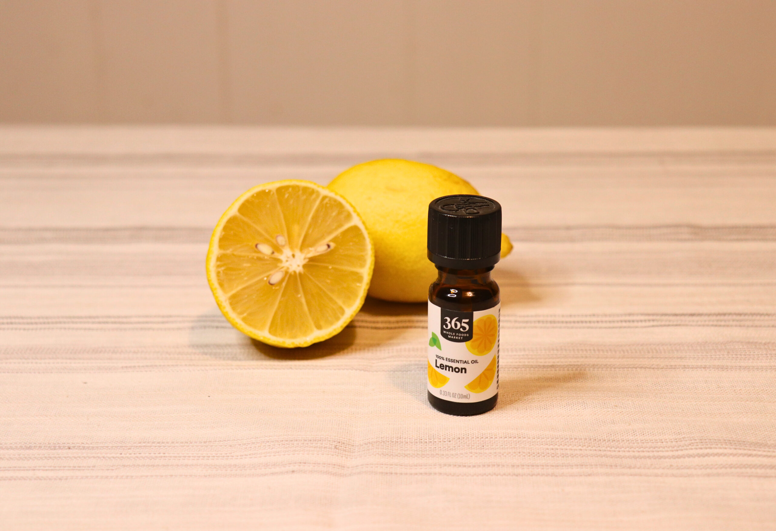 Lemons and a small bottle of lemon essential oil on a linen cloth.