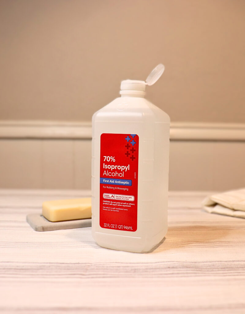 Bottle of rubbing alcohol on a linen cloth by a bar of natural soap for cleaning