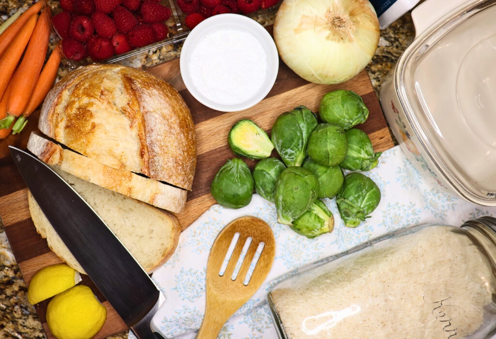 Lots of whole ingredients and cooking utensils laid out on a kitchen cabinet