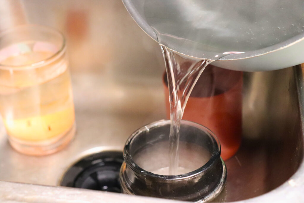 boiling water pouring into an old candle to melt the wax