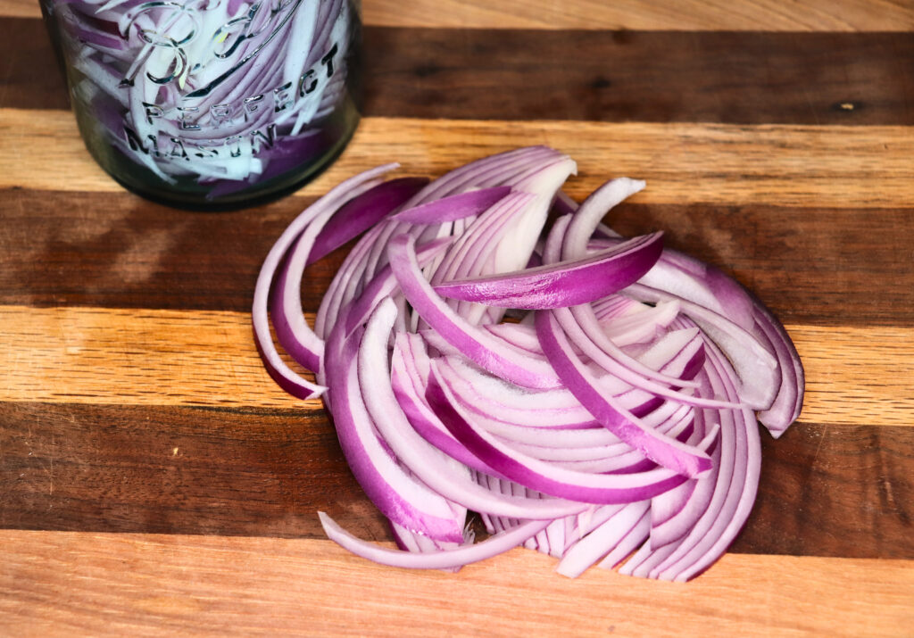 Sliced red onion next to a vintage mason jar