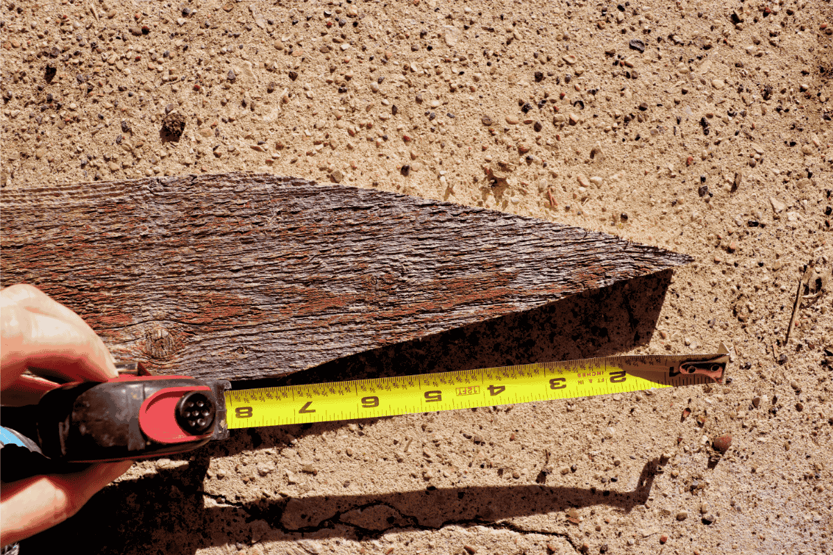 Wooden fence post with a 7 inch point being measured with yellow measuring tape