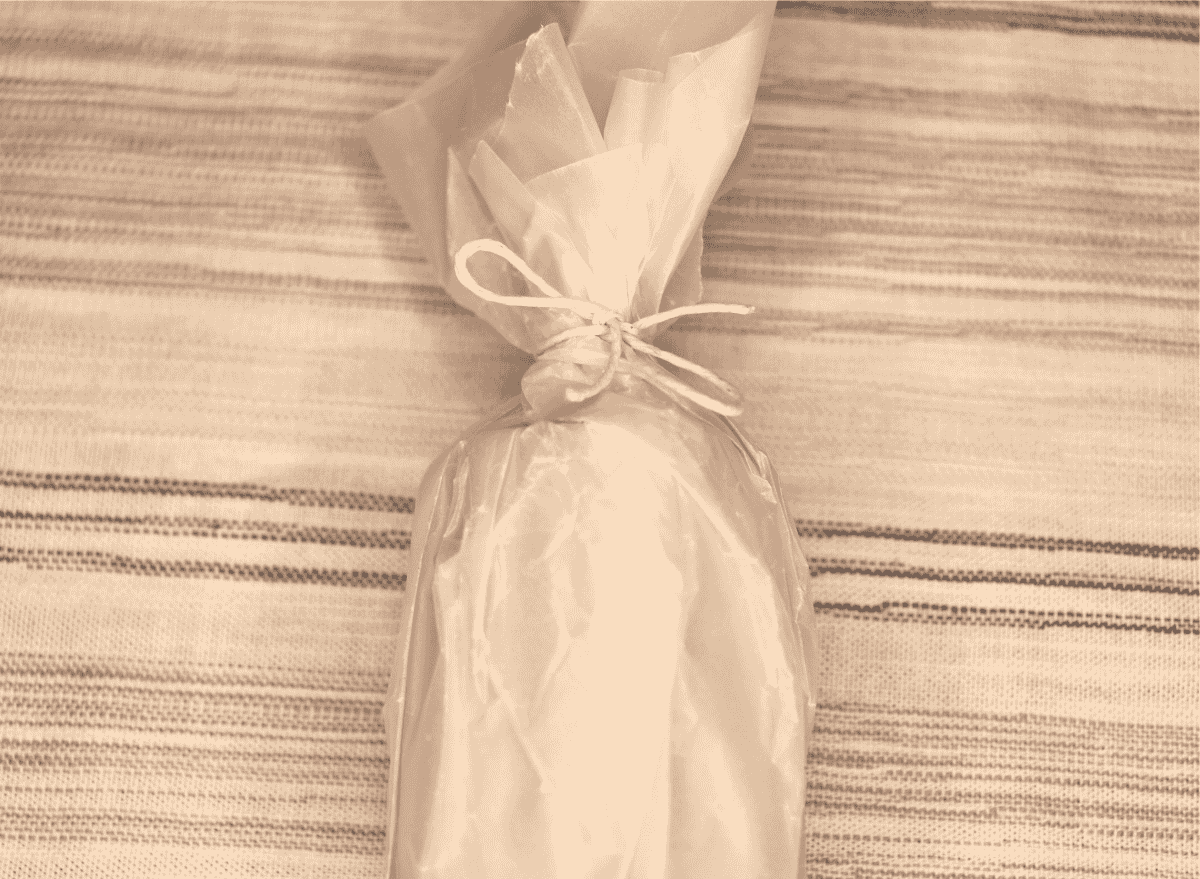 A knotted string securing wax paper around a lint fire starter log