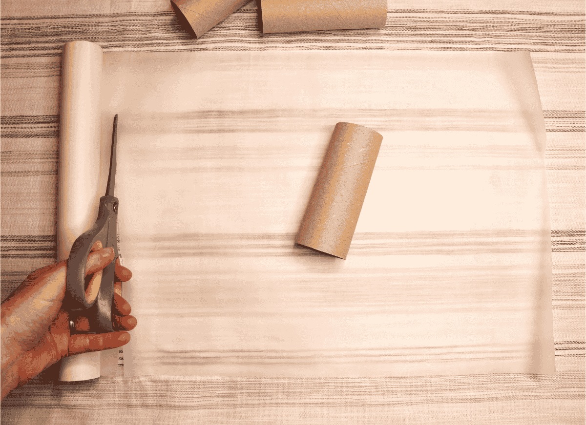 Cutting a square of wax paper with scissors with a toilet paper roll on top
