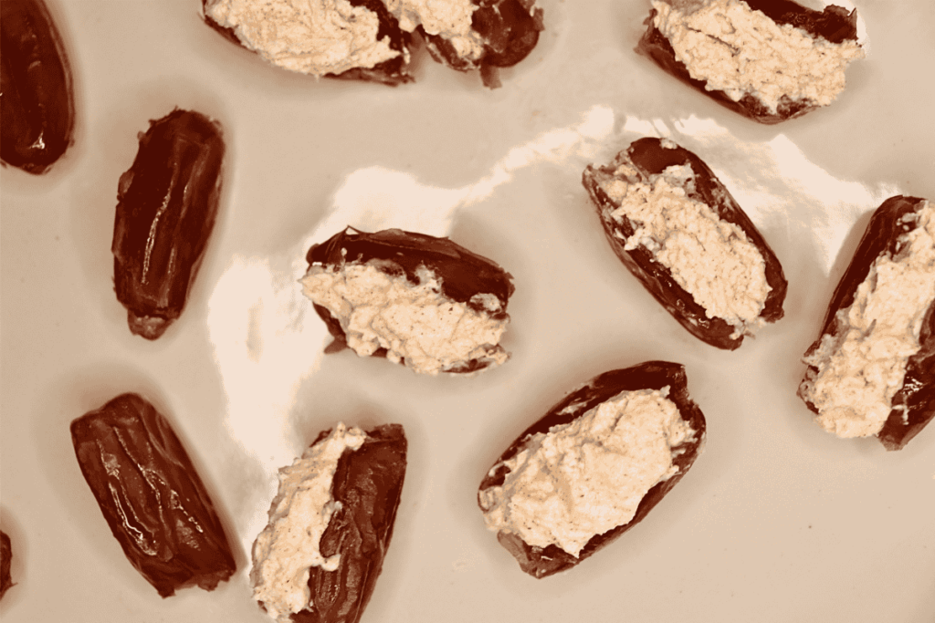 Process photo of dates stuffed with a goat cheese mixture next to some that are unstuffed.