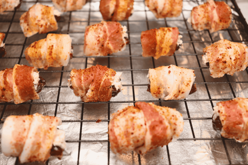 Bacon wrapped dates on a baking rack ready to bake.