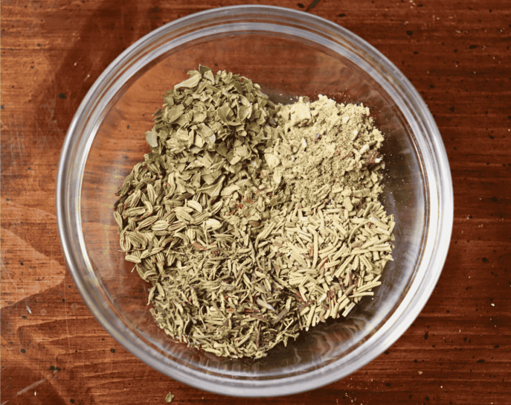 Six types of herbs in a glass bowl on a wooden table
