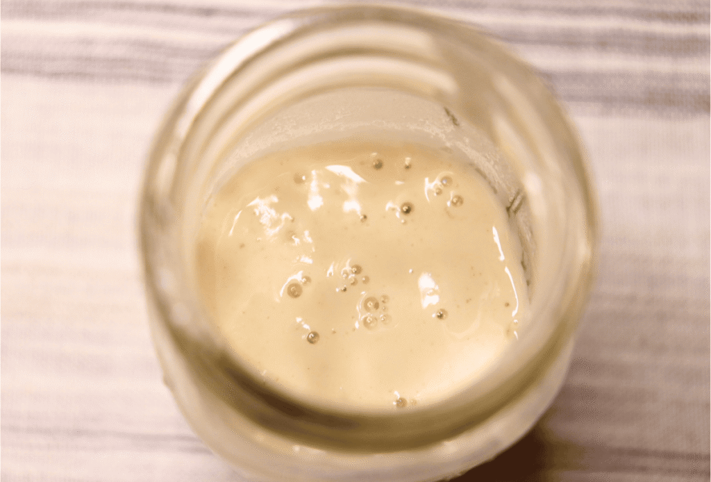 Immature sourdough starter bubbling in a small jar