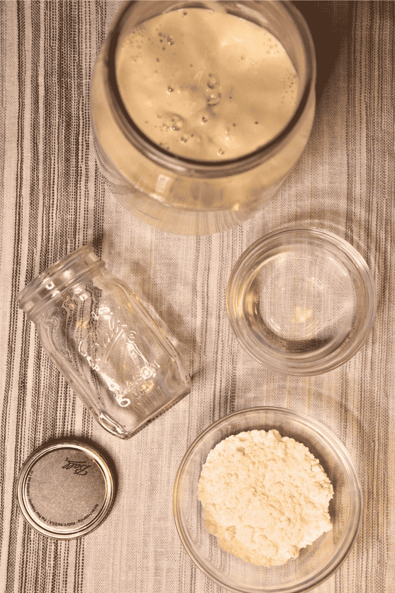 Materials including flour, water, discard, and a small jar laid out on a table
