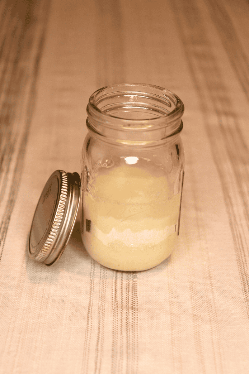 Small sourdough starter jar with unmixed flour, water, and starter inside
