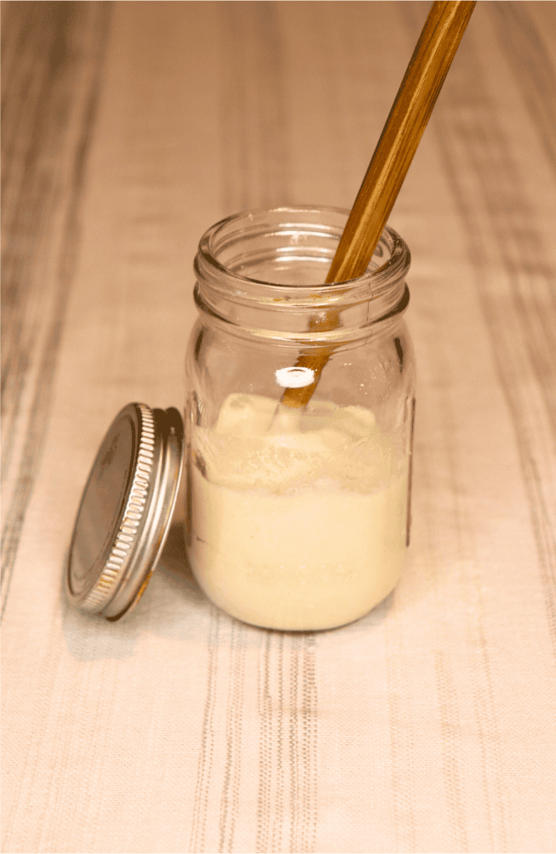 Mixed sourdough starter in a small jar with a wooden chopstick in it
