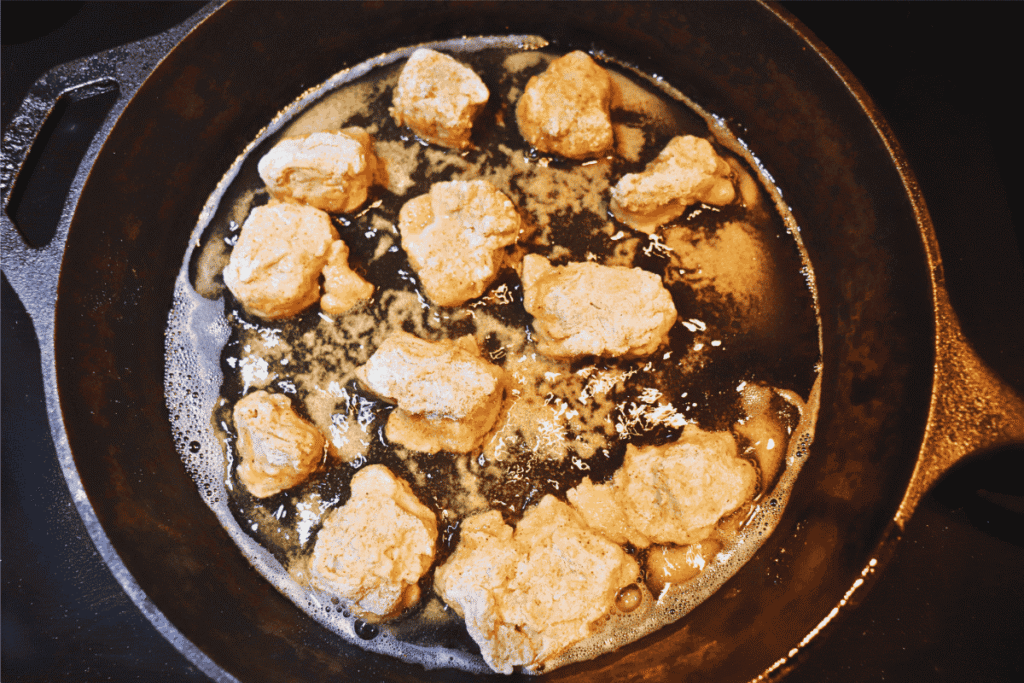 Homemade chicken nuggets frying in a cast iron skillet