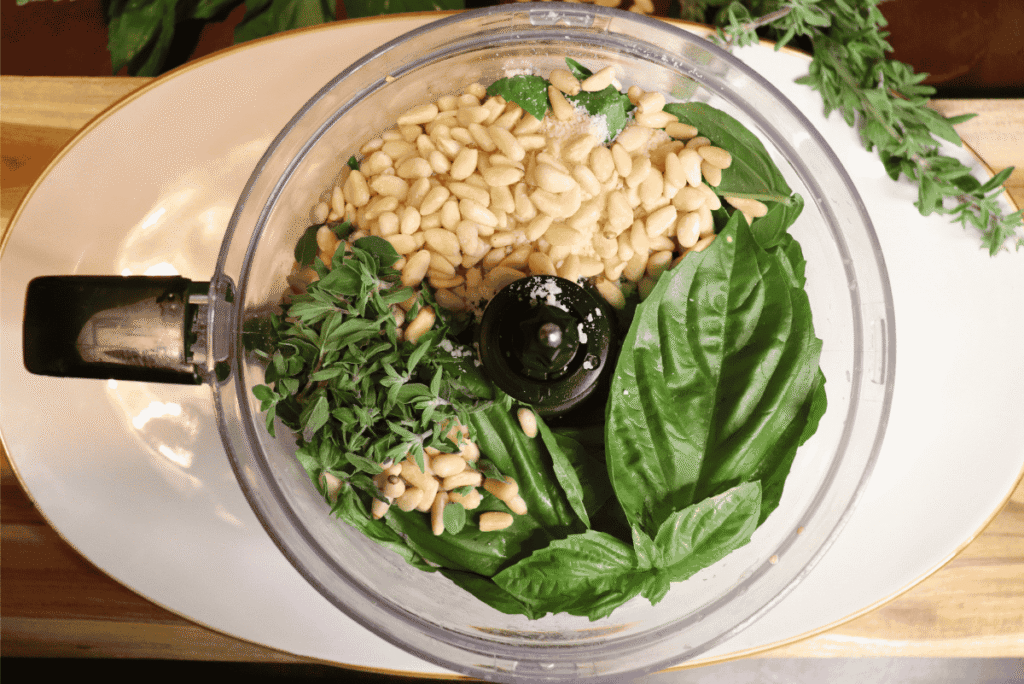 Food processor with homemade basil pesto ingredients inside