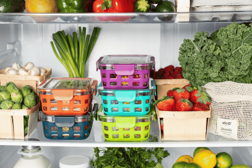 Fruits and vegetables organized in a fridge, being stored in cotton produce bags and glass containers.