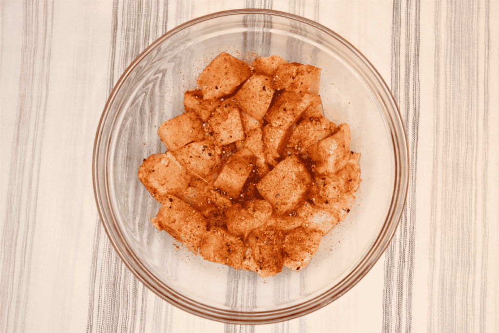 Chopped, seasoned chicken in a glass bowl