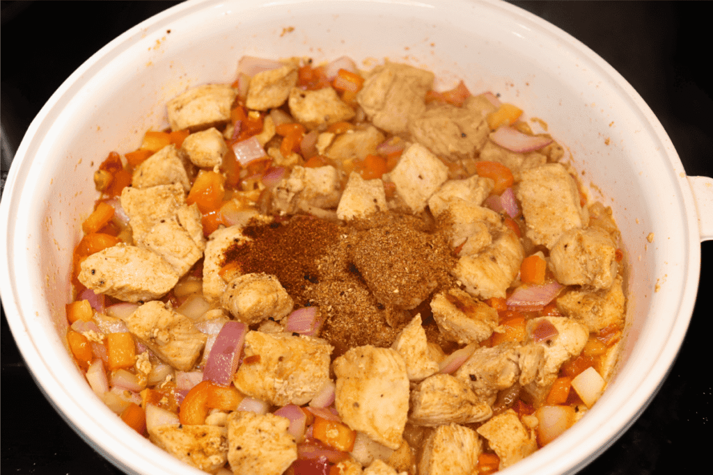 Chicken and vegetables cooking with spices piled on top