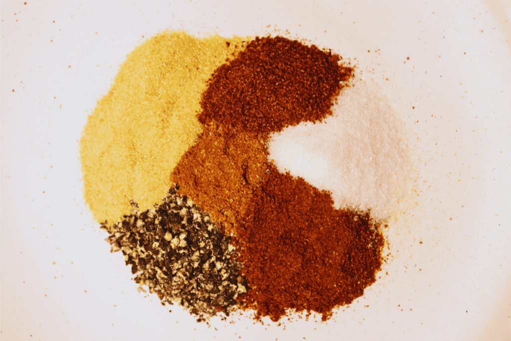 An arrangement of different spice powders on a white plate