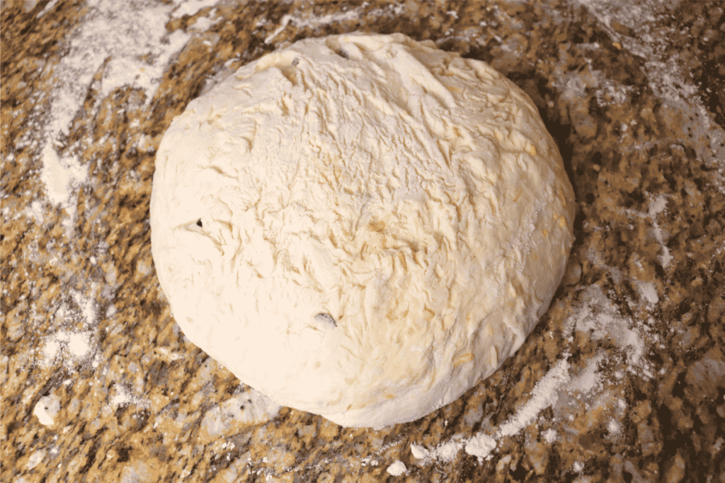 A shaped sourdough boule on a lightly floured countertop