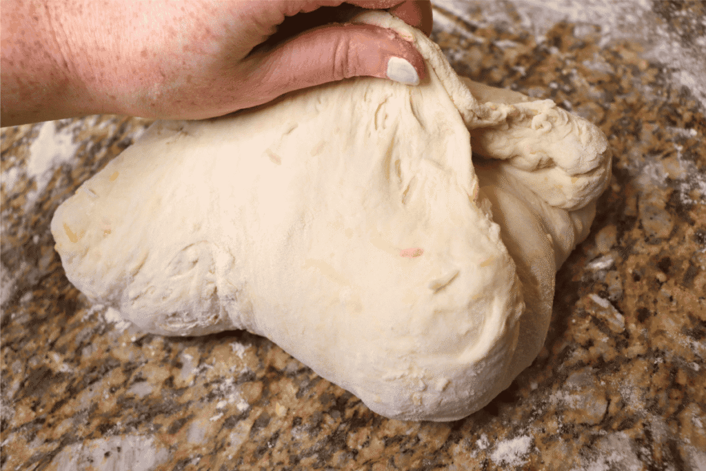 Close-up shot of sourdough being pinched into a seam on a countertop