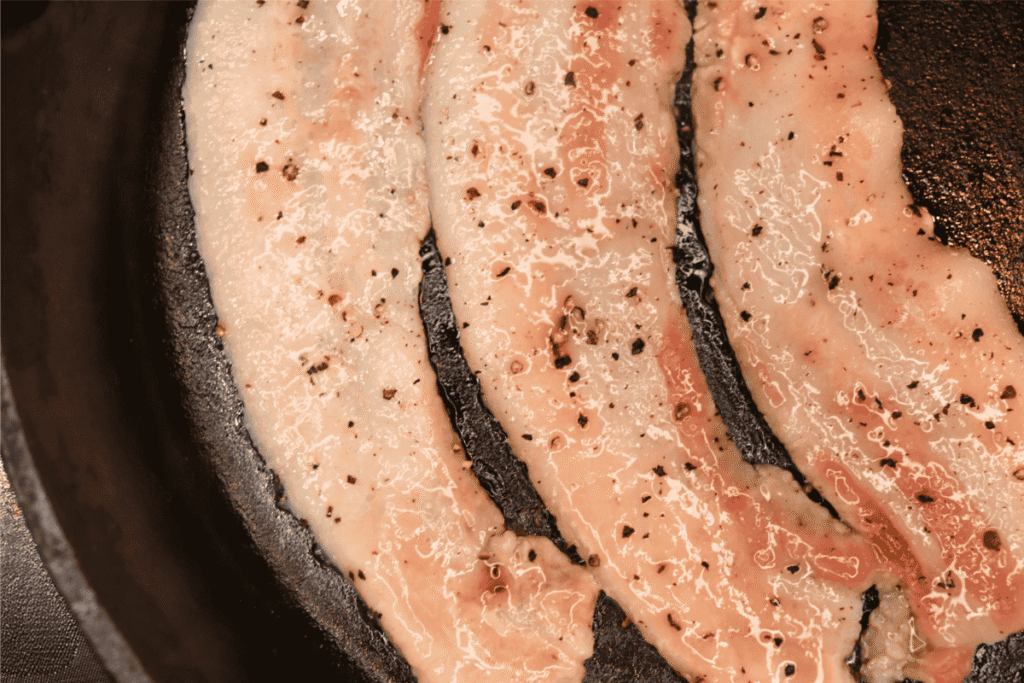 Seasoned bacon sizzling in a cast iron skillet