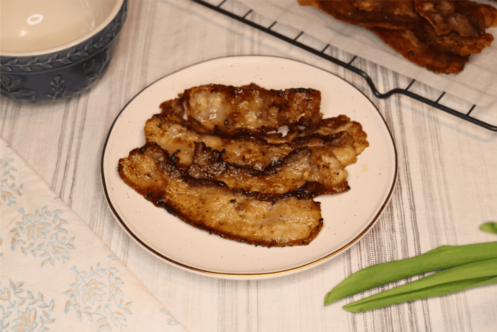 Cooked, golden bacon on a white plate