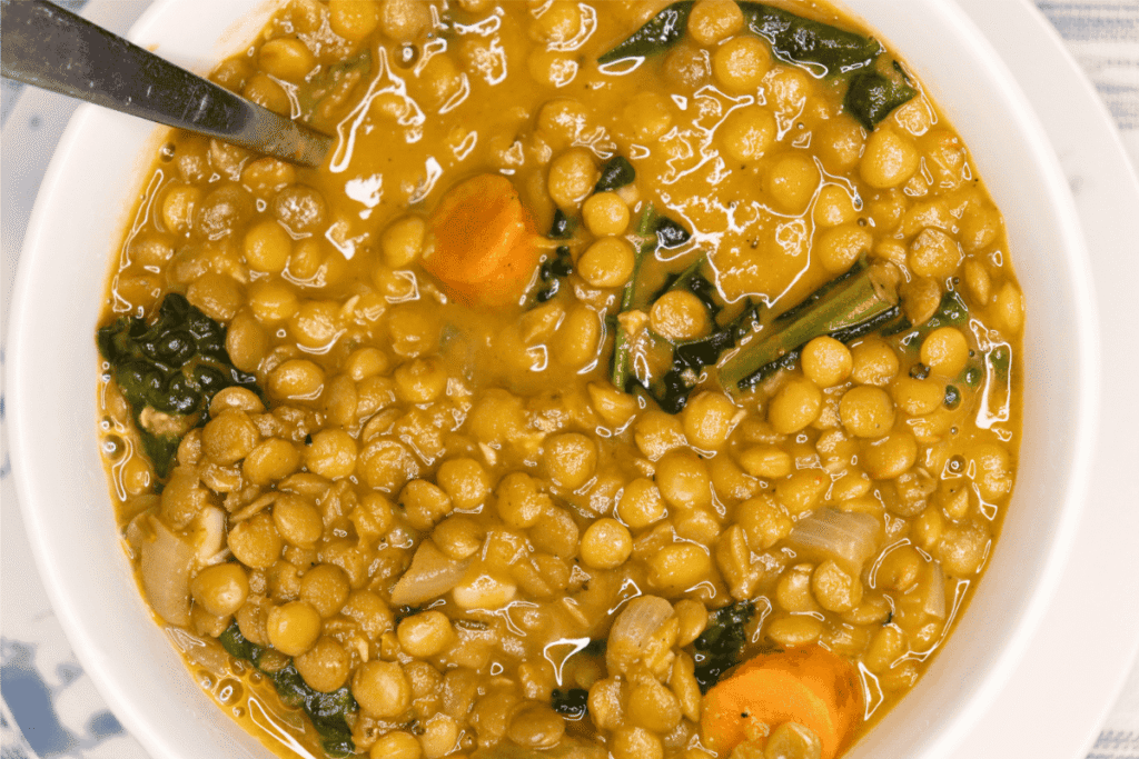 White bowl with creamy lentil soup with kale and carrots