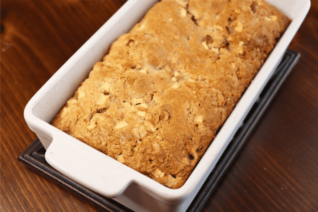 Baked apple bread loaf in a white ceramic loaf pan