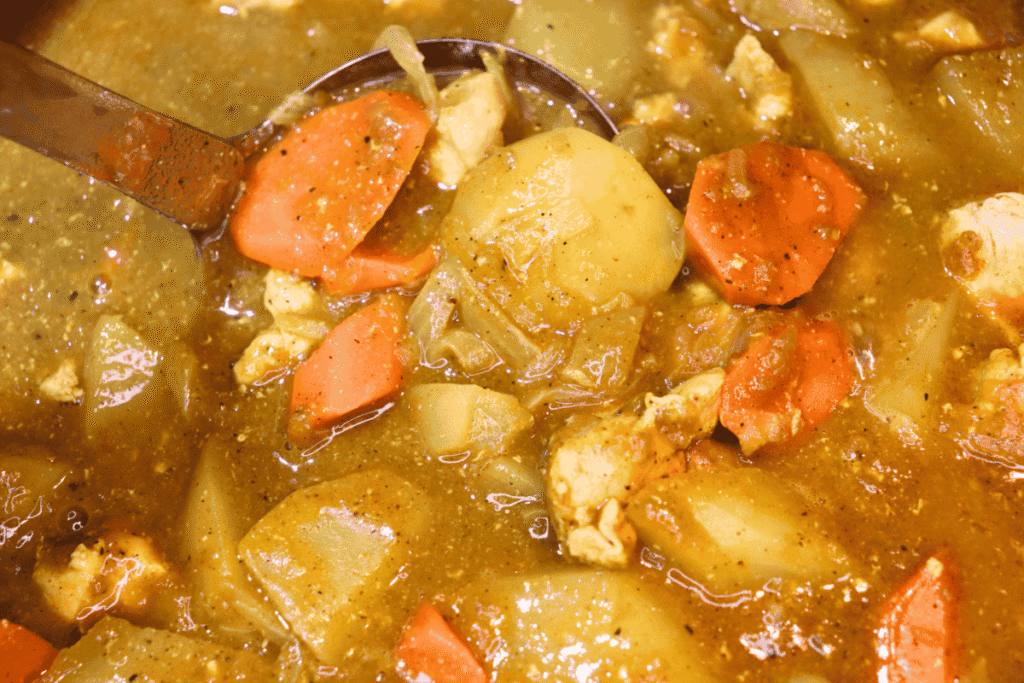 A close-up of a ladle of Japanese chicken curry in the pot
