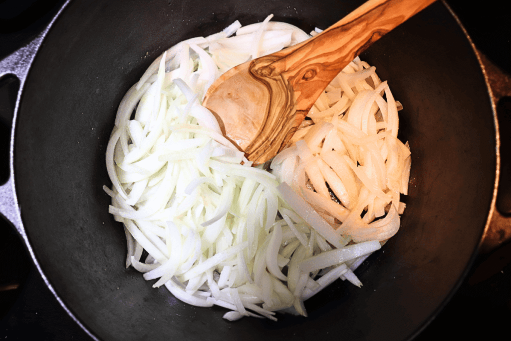 Sautéing onions in a dutch oven with a wooden spoon
