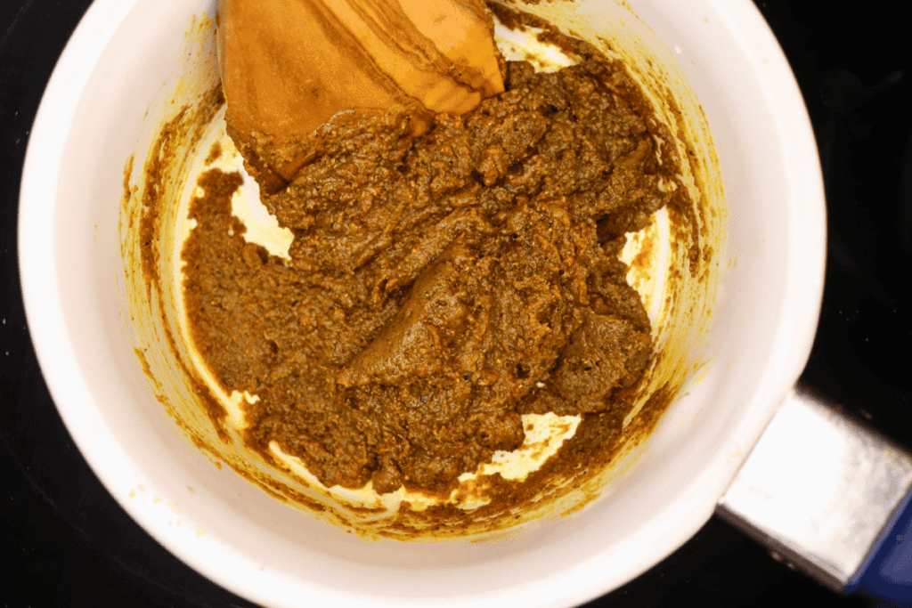Stirring a thick, brown roux with a wooden spoon