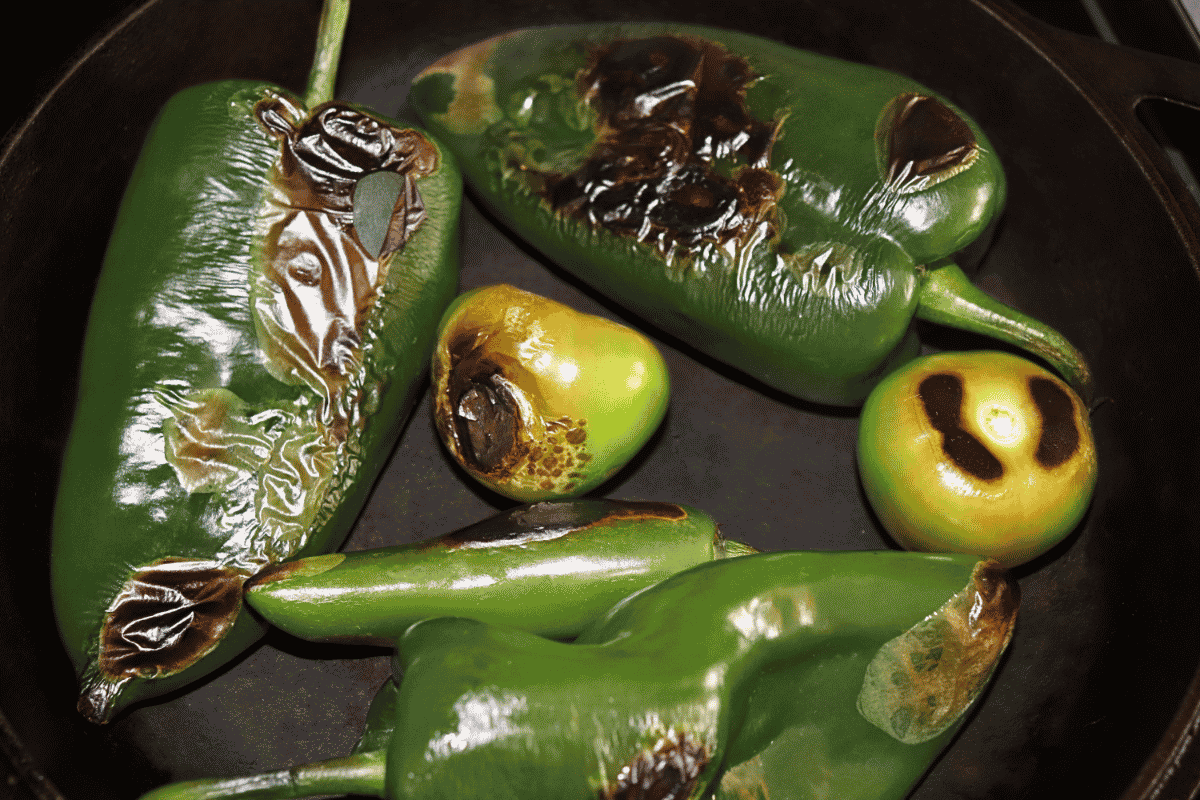 Charred peppers and tomatillos in a cast iron skillet