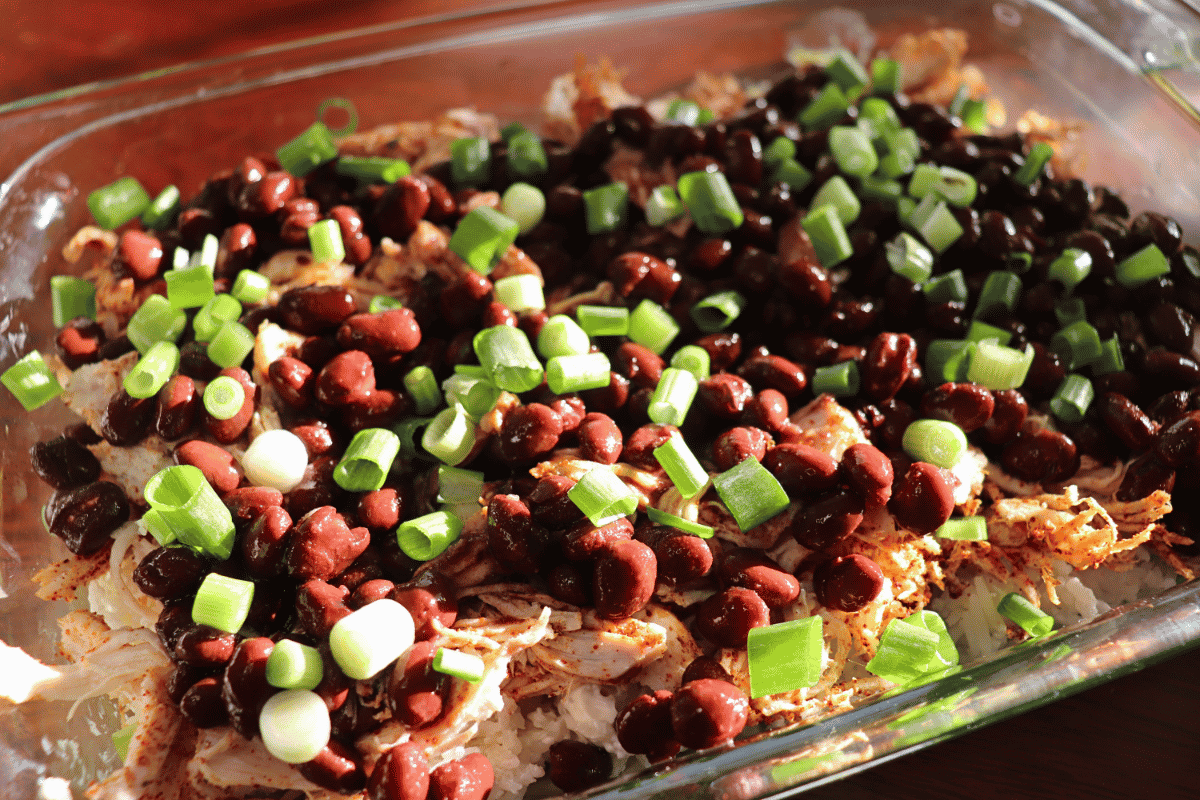 Layers of a chicken enchilada casserole that is almost complete