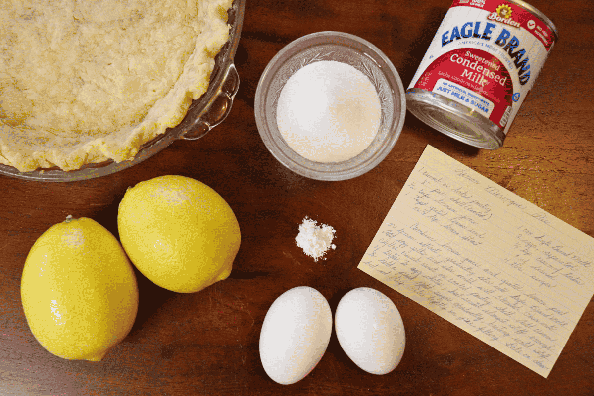 Ingredients for a lemon meringue pie arranged on a wooden surface