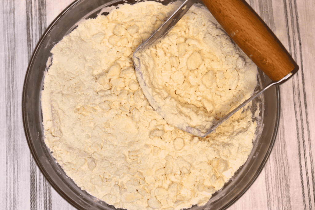 Flour and butter being cut together with a handheld pastry cutter
