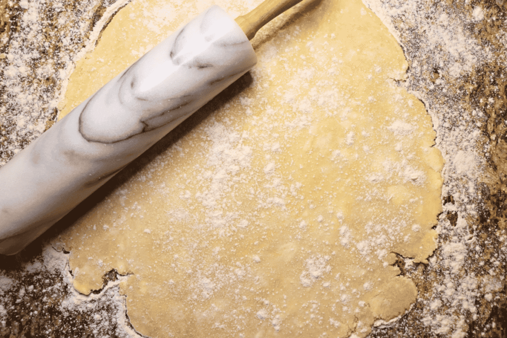 pie crust rolled out on a counter under a marble rolling pin